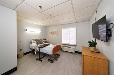 Brightly lit resident room with bed and TV