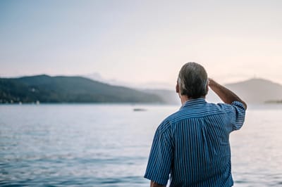 An older man looking at the serene lake landscape