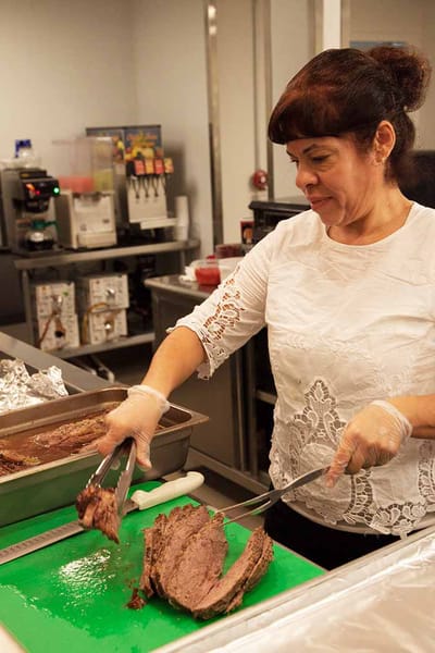 Staff member slicing roast beef in the kitchen