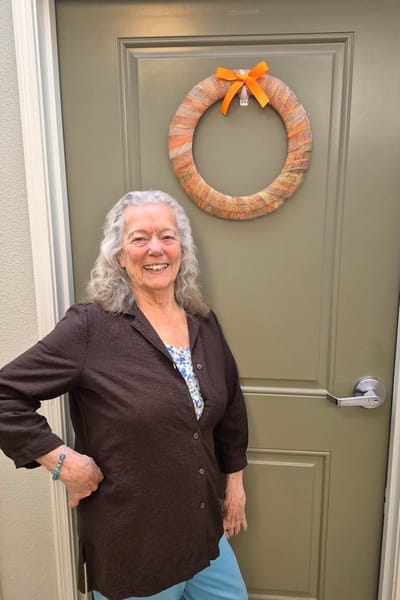 A resident posing happily in front of her door