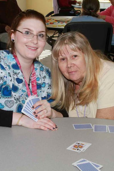 Staff and a resident playing cards together