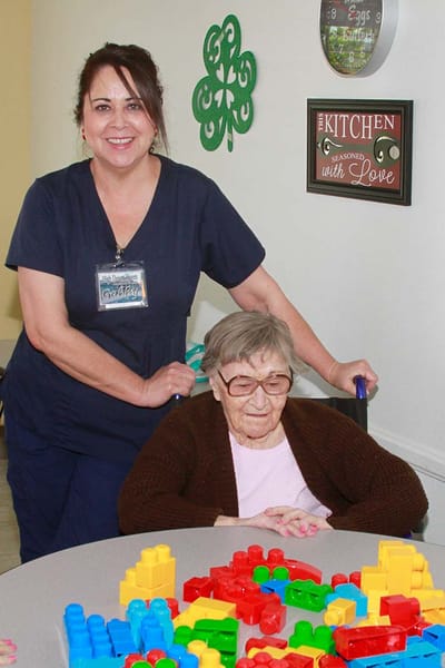 Staff member assisting a resident with colorful blocks