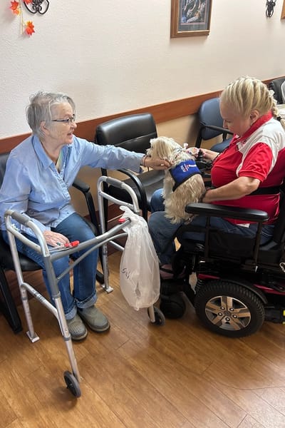 Caregiver interacting with a resident and a small dog