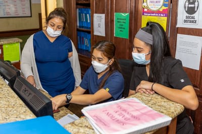 Staff members assisting at reception desk with safety protocols