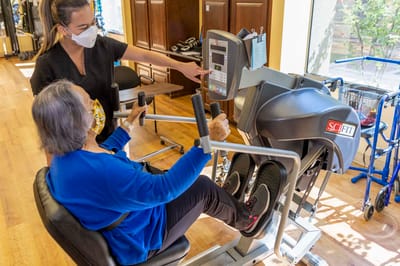 Staff assisting a resident with exercise equipment
