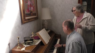 A resident engaging in music with staff assistance