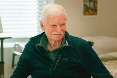 An elderly man smiling in a bright room