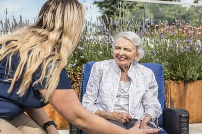 A staff member interacting with a smiling resident outdoors