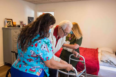 Staff assisting an elderly resident with a walker