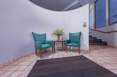 A cozy corner with two teal chairs and a flower arrangement