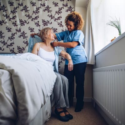 A caregiver assisting a resident in a bright room