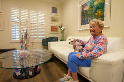 A resident sitting with a dog in a cozy lounge
