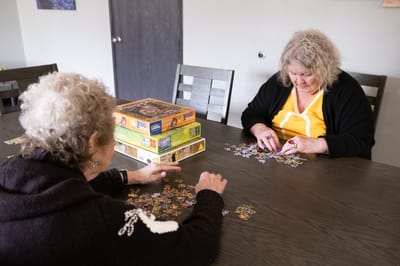 Two residents working on a jigsaw puzzle at a table