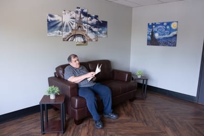 Resident reading in a lounge area with wall art