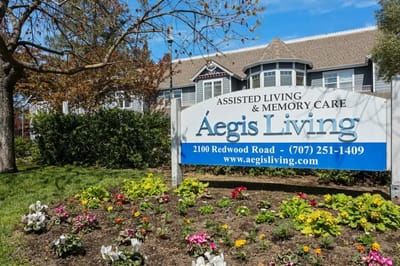 Exterior view of Aegis Living facility with sign and flowers