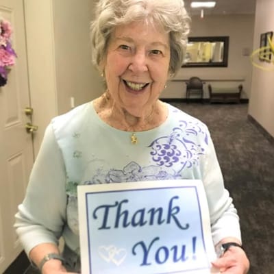 A resident smiling and holding a 'Thank You' sign