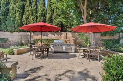 Outdoor seating area with red umbrellas and BBQ grill