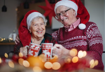 Couple celebrating with festive mugs and hats