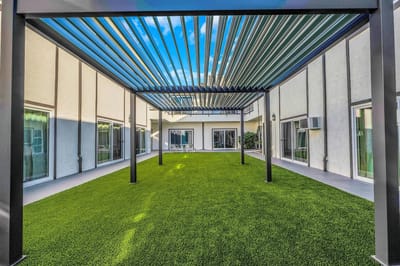 Outdoor area with artificial grass under a pergola.