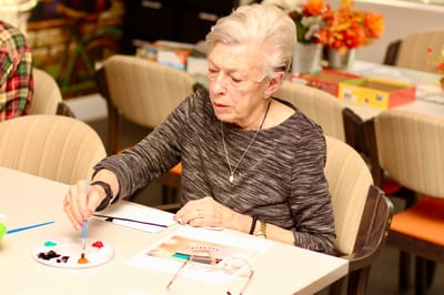 Resident painting in a bright activity room