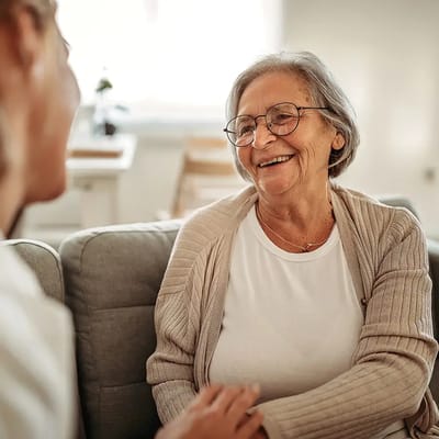 Laughing elderly woman chatting with caregiver