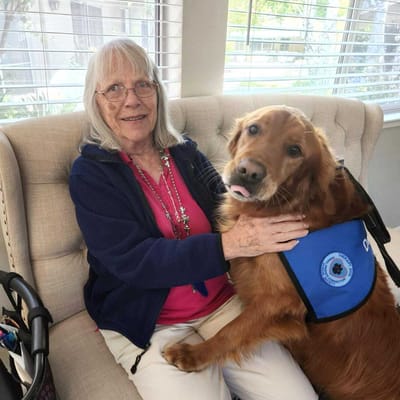 Resident enjoying time with a therapy dog in a lounge