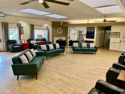 Bright common area with green sofas and wooden floor
