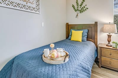 A cozy resident bedroom with a blue quilt and snacks