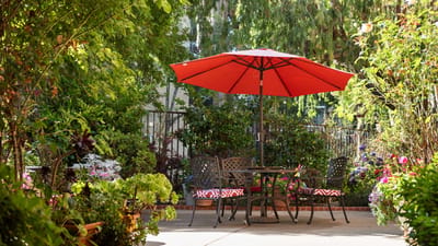 Outdoor seating area with red umbrella and flowers