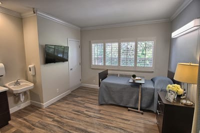 Interior view of a private resident room with a bed and TV