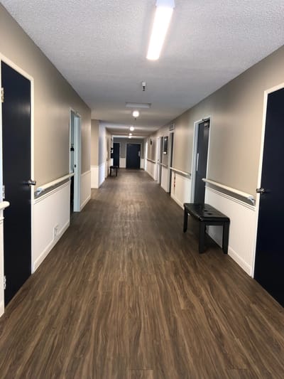 Well-lit hallway with doors and wood flooring