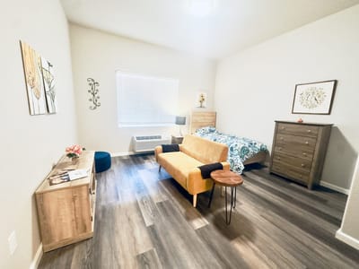 A well-furnished resident room with a bed and seating area