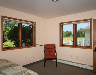 A simple resident room with windows and a chair