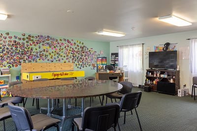 A colorful activity room with a large table and artwork on the walls