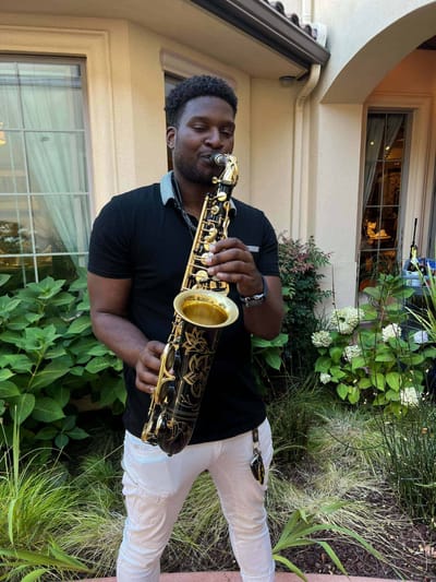 Musician playing saxophone in a garden area
