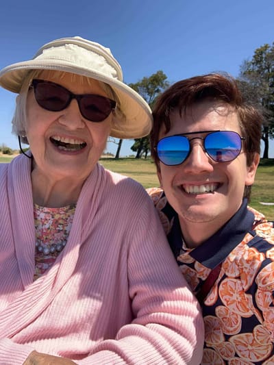 A smiling resident with a staff member outdoors