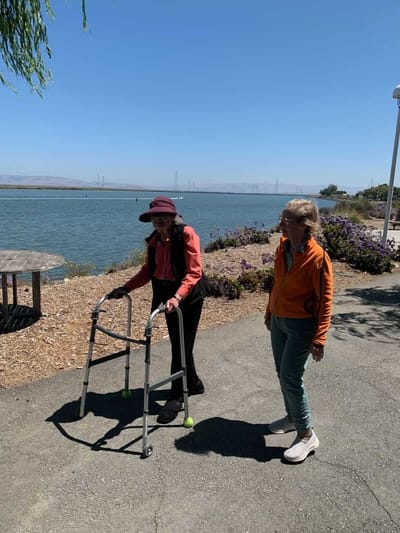 Two residents walking along a path by the water