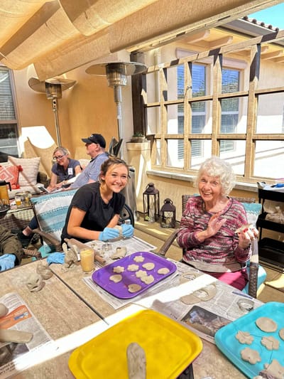 Residents participating in a clay modeling activity outdoors