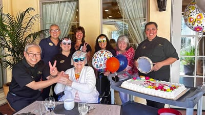 Staff and residents celebrating a birthday with balloons and cake