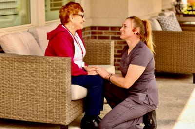 Staff member engaged with a resident in an outdoor seating area
