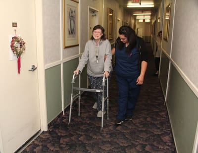 Staff assisting a resident in the hallway of the facility