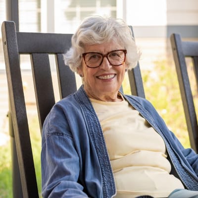 Smiling elderly woman sitting outside in a rocking chair