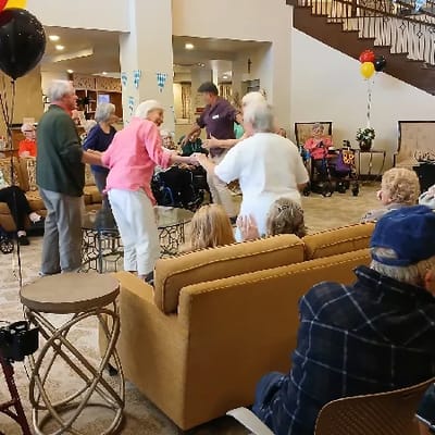 Residents and staff dancing in a festive common area