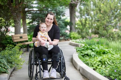 A woman in a wheelchair enjoying a garden path with a child