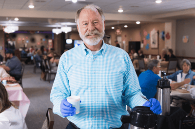 A staff member serving coffee to residents in the dining area