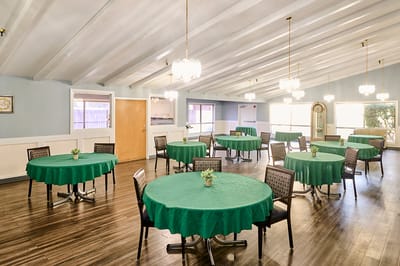 Bright dining room with green tablecloths and chairs