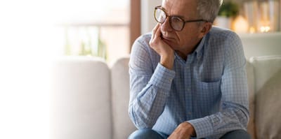 An elderly man thinking while seated indoors