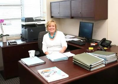 Staff member smiling at their desk in a bright office