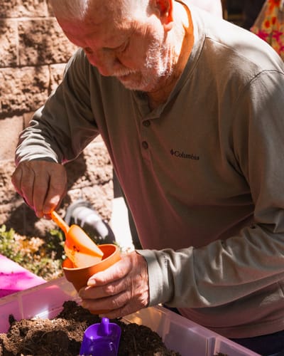 An elderly man planting in a pot during an activity.