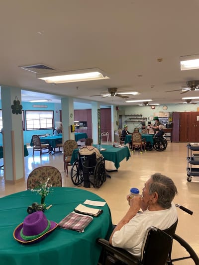 Residents enjoying time in a common area with green tables